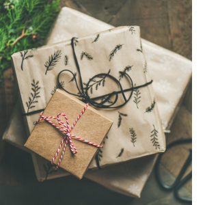 pile of wrapped gifts wrapped in brown paper with red and white ribbon on a wooden table