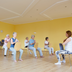 people participating in chair yoga in a room with a yellow wall